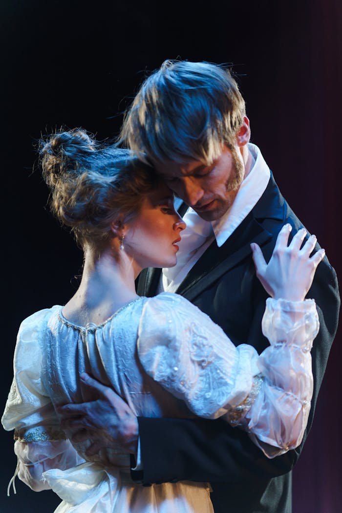 about-us-02 Romantic theatrical moment with actors embracing onstage.